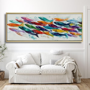 Può includere: Dipinto rettangolare incorniciato raffigurante un banco di pesci colorati. I pesci sono dipinti in vivaci tonalità di rosso, arancione, giallo, verde, blu e viola. L'opera d'arte è esposta sopra un divano bianco.
