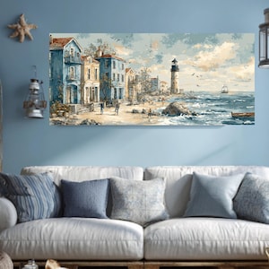 May include: A coastal landscape painting featuring buildings in shades of blue and yellow, a lighthouse, and a sailboat on the sea. The artwork depicts a beach scene with figures, birds, and a small boat. The painting is displayed above a white sofa with blue pillows.