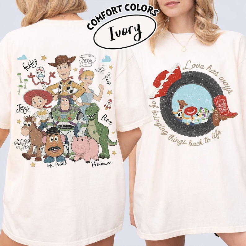 May include: An ivory t-shirt featuring a graphic print of Toy Story characters including Woody, Buzz Lightyear, Jessie, Rex, Hamm, Bullseye, Forky, and Bo Peep on the back, with a circular graphic and the text Love has ways of bringing things back to life on the front.