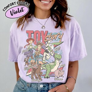 May include: Violet Comfort Colors t-shirt featuring a Toy Story graphic. The design includes characters like Woody, Buzz Lightyear, and Rex. The text "Toy Story" is prominently displayed, along with "Jessie Since 1995".