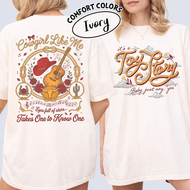 May include: An ivory t-shirt featuring two graphic designs. The back displays a red cowboy hat, acoustic guitar, roses, a horseshoe, and a steer skull with the text Cowgirl Like Me and Eyes full of stars... Takes One to Know One. The front shows the text it's a Toy Story Baby, just say yes in rope-style lettering.