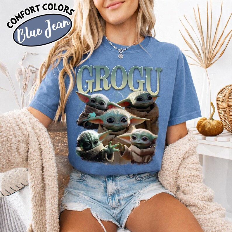 May include: Blue t-shirt with the word "GROGU" in a light green font and an image of Grogu, also known as Baby Yoda, from The Mandalorian. The shirt has the words "COMFORT COLORS" and "Blue Jean" in a circle at the top left.