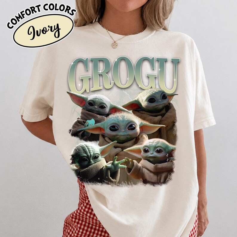 May include: Ivory-colored t-shirt featuring a graphic of Grogu, also known as Baby Yoda, with the word "GROGU" above the image. The graphic shows Grogu in various poses. The shirt has the words "COMFORT COLORS" and "Ivory" in a circle.