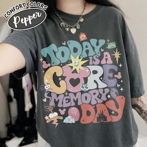 May include: Dark grey Comfort Colors t-shirt featuring the text "Today is a Core Memory Day" in colourful, retro lettering. The design includes cartoon characters and a castle illustration. The shirt has a relaxed fit.