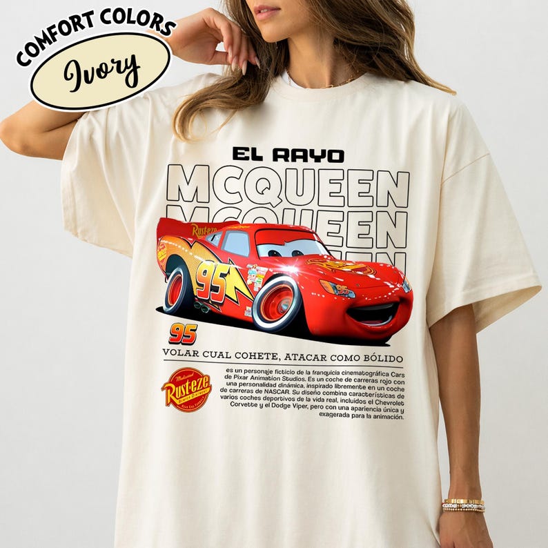 May include: Ivory-colored t-shirt featuring a graphic of the character Lightning McQueen from the movie Cars. The design includes the text "EL RAYO MCQUEEN" and "95". The shirt also has the "Rusteze" logo.