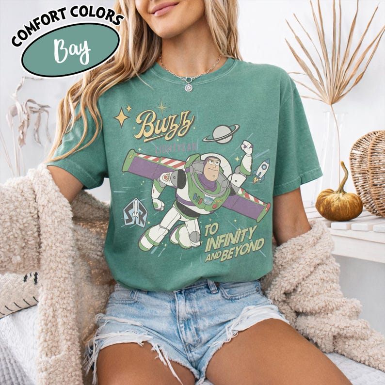 Może przedstawiać: Zielona koszulka z Buzzem Astralem, napisem "Buzz Lightyear" i "To Infinity and Beyond". Koszulka ma stylizowany design z planetą i rakietą.