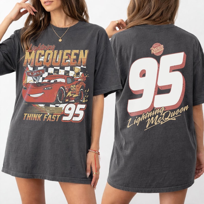 May include: Dark grey t-shirt featuring Lightning McQueen from the Cars film. The front graphic includes McQueen, the number 95, and the text "THINK FAST". The back displays a large "95" and "Lightning McQueen" text.