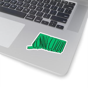 Peut inclure: Un autocollant vert en forme de l'État du Connecticut. Le mot "CONNECTICUT" est écrit en script noir à l'intérieur du contour vert. L'autocollant est sur un ordinateur portable.