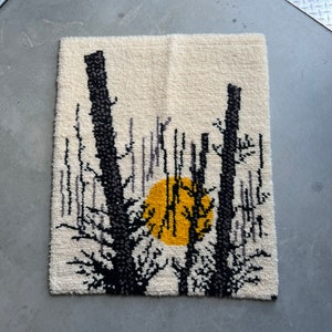 May include: A white wall tapestry with a black and yellow design of trees and a sun. The trees are stylized and have a minimalist design.