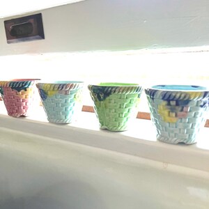 May include: Four small ceramic planters in a basket weave design. The planters are in shades of pink, blue, green, and light blue.