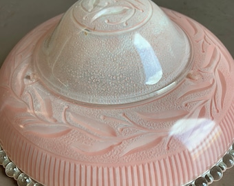 May include: A pink glass light fixture with a beaded edge and a floral design. The top of the fixture is domed and has a swirl design.