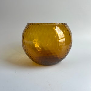 May include: A round, amber-colored glass vase with a textured surface.