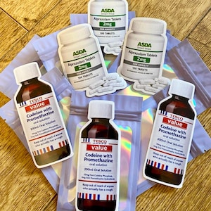 Może przedstawiać: Asortyment wyciętych naklejek przedstawiających butelki z lekami i etykiety. Etykiety zawierają tekst dla Alprazolam Tablets i Codeine with Promethazine oral solution. Butelki są białe i brązowe z białymi zakrętkami.
