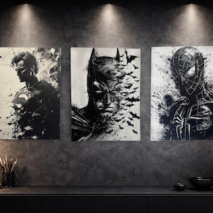 Peut inclure: Ensemble de trois impressions d'art de super-héros en noir et blanc. Les impressions présentent Superman, Batman et Spider-Man dans un design stylisé et abstrait. L'œuvre est exposée sur un mur gris foncé au-dessus d'un meuble noir.