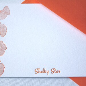 May include: A white card with an orange envelope. The card has a border of orange ginkgo leaves and the text "Shelby Star" printed in orange.
