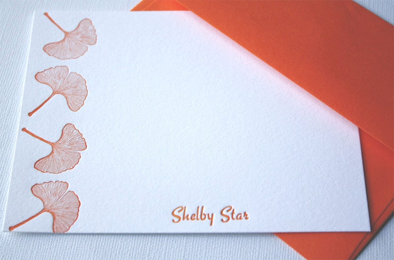 May include: A white card with an orange envelope. The card has a border of orange ginkgo leaves and the text "Shelby Star" printed in orange.