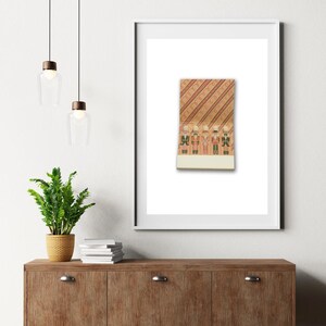 May include: A framed print featuring a vintage matchbook design. The matchbook illustration depicts five toy soldiers in uniform against a background of diagonal stripes and a repeating pattern. The print is displayed on a white background.