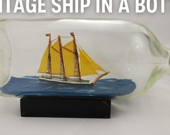 Barco antiguo en una botella: goleta artesanal con velas amarillas