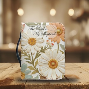 May include: A floral-themed book cover with the text "The Lord is My Shepherd." The cover features large white and peach-colored daisies with yellow centers, green leaves, and a black handle. The design is set against a blurred background.