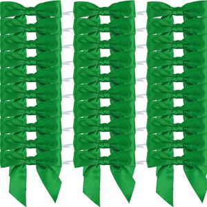 May include: A collection of thirty bright green satin ribbon bows arranged in three vertical columns. Each bow features a smooth, shiny finish with two short, pointed tails extending downward, attached to a thin, flexible wire tie for fastening.