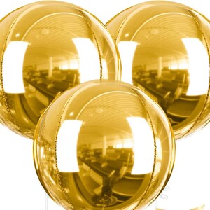 May include: Three gold metallic sphere balloons. The balloons have a reflective surface, with vertical seams and a shiny, golden appearance. The balloons are round and appear to be inflated, reflecting the surrounding environment.
