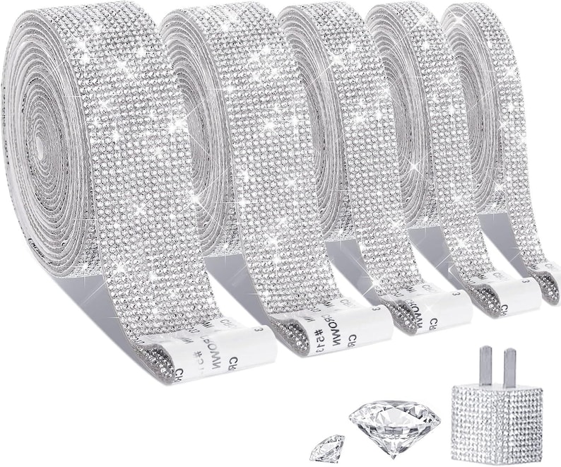 May include: Five rolls of silver-toned adhesive ribbon covered in small, reflective faux rhinestones. Each roll features a white backing strip with the text CROWN #541. Also included are two loose, clear, faceted diamond-shaped decorative accents.