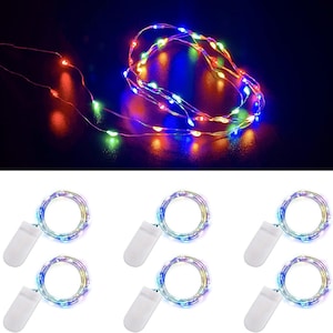 May include: A set of six battery-operated string lights featuring thin, flexible copper wire with small, multi-colored LED bulbs. The lights emit red, green, blue, and yellow illumination, and each strand is connected to a white plastic battery pack.