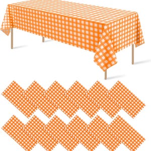 May include: A rectangular table covered with an orange and white checkered tablecloth, accompanied by a collection of twelve matching orange and white gingham napkins arranged in two rows below the table.