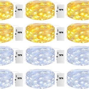 May include: A collection of twelve coiled string light sets, each featuring a thin wire and a small white battery pack. Six sets emit a warm yellow glow, while the other six sets emit a cool white light, all arranged in a grid pattern.