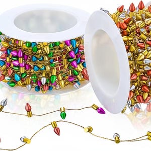 May include: Two white plastic spools wrapped with thin gold wire strings featuring small, multi-colored, teardrop-shaped decorative bulbs in shades of red, green, blue, silver, and gold, extending outward from the spools in a continuous line.