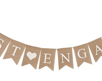 May include: A banner with the words "JUST ENGAGED" in white letters on individual tan pennants. A white heart is between the words. The banner is strung on a thin, silver-colored string.