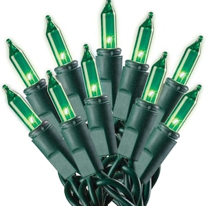 May include: A cluster of miniature string lights featuring translucent green glass bulbs. Each bulb is set into a dark green plastic base, connected by a dark green insulated wire. The lights are arranged in a fan-like formation, glowing with a soft green light.