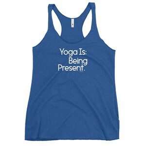 Peut inclure: Un débardeur dos nageur bleu roi avec le texte blanc Yoga Is: Being Present. imprimé sur le devant. Le vêtement présente une encolure dégagée et un design sans manches, avec une petite étiquette de marque blanche visible au niveau du col.