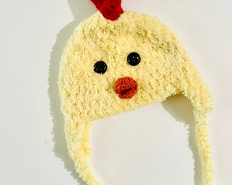 May include: A yellow crocheted chick hat with red comb and black eyes. The hat has a long tail and is perfect for a baby or toddler.