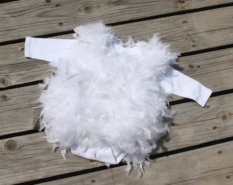 May include: White baby onesie with a fluffy white feather trim. The onesie is made of soft, comfortable fabric and is perfect for a special occasion.
