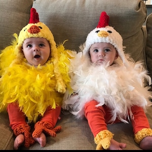 May include: Two babies dressed in chicken costumes. One baby is wearing a yellow chicken costume with yellow feathers and orange feet. The other baby is wearing a white chicken costume with white feathers and orange feet.