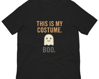 May include: Black t-shirt featuring the phrase "THIS IS MY COSTUME." above a ghost graphic and the word "BOO." in grey. The ghost is white with a light beige face, a simple design for Halloween.
