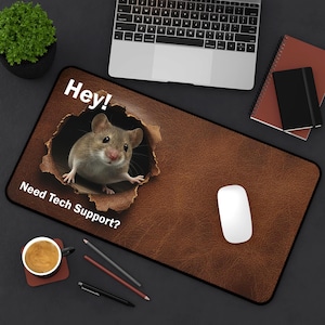 May include: Brown mouse mat with a distressed leather effect. A cartoon mouse emerges from a torn hole, with the text "Hey!" and "Need Tech Support?" A white computer mouse is on the right.
