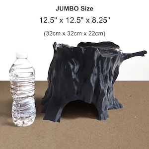 May include: A dark grey, hollow tree stump replica with a textured bark surface and a large arched opening at the base. The text reads JUMBO Size 32cm x 32cm x 22cm. A clear plastic water bottle is placed next to the stump for scale.