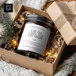 Puede incluir: Una vela en tarro de cristal marrón con tapa negra, dentro de una caja de cartón con papel triturado y luces de hadas. La vela tiene una etiqueta blanca con el texto "FOR ANY LABEL SIZE AND SHAPE" y "250G". También hay una pequeña caja de regalo.
