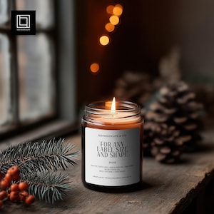 May include: A lit scented candle in a clear glass jar with a white label that reads "FOR ANY LABEL SIZE AND SHAPE". The candle sits on a wooden surface with a blurred background of lights and pine cones. The candle is 250g.