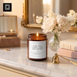 May include: A lit candle in an amber glass jar with a white label that reads 1001MOCKUPS & CO. FOR ANY LABEL SIZE AND SHAPE 250G. The candle features a visible flame and is positioned on a white surface next to a gold metal candle snuffer.