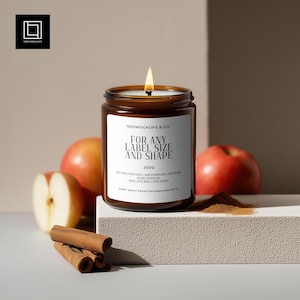 以下が含まれることがあります： 「FOR ANY LABEL SIZE AND SHAPE」と書かれた白いラベルが付いた、点灯した茶色のガラスのキャンドルジャー。キャンドルの周りにはリンゴ、シナモンスティック、シナモンパウダーの山があります。キャンドルの重量は250gです。