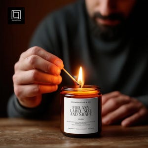 May include: A lit candle in a brown glass jar with a white label. The label reads "FOR ANY LABEL SIZE AND SHAPE" and "250G". A match is being used to light the candle. The candle is on a wooden surface.