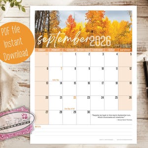 May include: A September 2026 calendar page featuring a photograph of autumn trees with yellow and orange leaves at the top. The calendar grid includes dates, the text "Labor Day," "First Day of Fall," and a quote by Henry David Thoreau at the bottom.