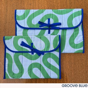May include: Two quilted fabric cases with a light blue background and a green, wavy pattern. The cases have a blue trim and a blue ribbon closure. The text "GROOVE BLUE" is at the bottom.