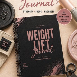 Op de afbeelding: Een zwart spiraalgebonden gewichthefjournaal met roségouden tekst "WEIGHT LIFT JOURNAL" en "STRONG MIND, STRONG BODY, YOU." De kaft heeft roségouden penseelstreekaccenten. Het journaal is gemarkeerd als een printbare digitale download.