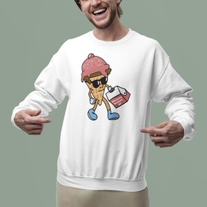 May include: White sweatshirt featuring a cartoon ice cream cone character wearing sunglasses and holding a box labeled "Emergency Meltdown Kit." The ice cream cone has a pink scoop with sprinkles and a waffle cone base. The character is wearing blue shoes.