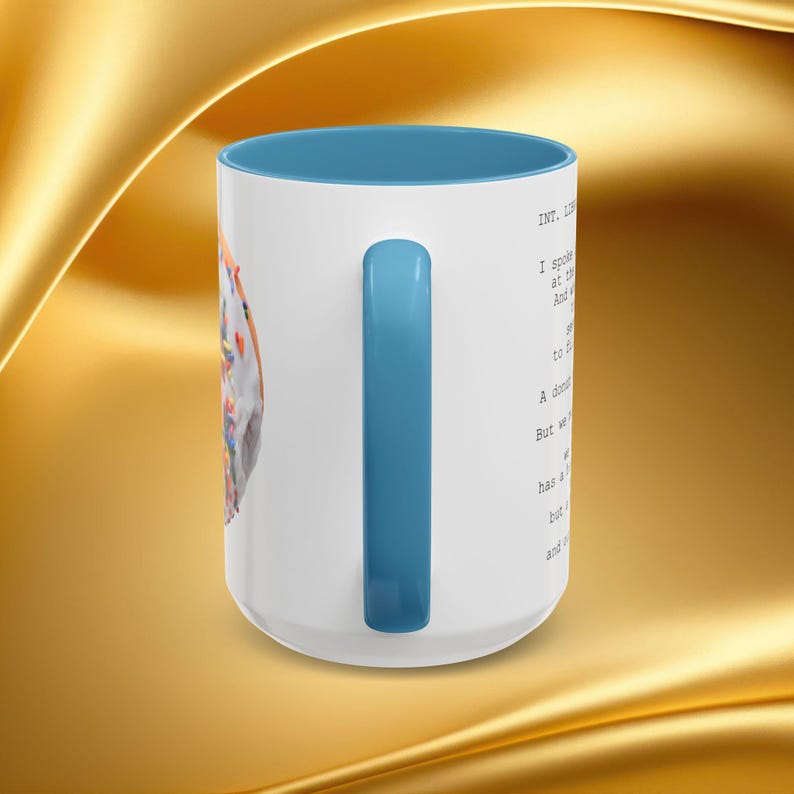 K&ouml;nnte beinhalten: Wei&szlig;er Keramikbecher mit blauem Innenraum und Griff. Der Becher hat ein Donut-Design mit bunten Streuseln und Text auf der Seite. Der Becher steht vor einem goldenen Hintergrund.