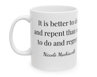 Puede incluir: Taza de cerámica blanca con asa curva. La taza presenta un texto negro que dice "Es mejor hacer y arrepentirse que no hacer y arrepentirse" y el nombre "Niccolò Machiavelli".